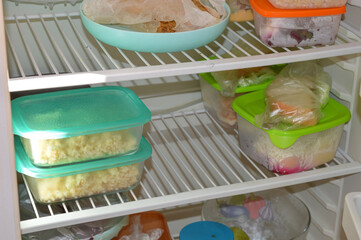 Open refrigerator with food storage in plastic containers and jars. Concept of meal prep, homemade...