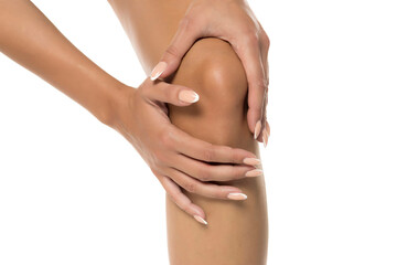 Studio shot of woman's hands gripping knee in pain, bodycare and