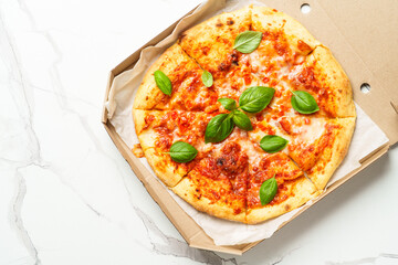 Pizza Margarita in a cardboard box on white background.