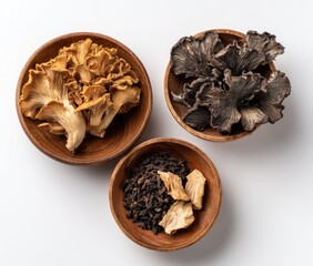 Three wooden bowls hold dried mushrooms and spices.  Two bowls contain various dried mushrooms; one is light brownish-tan, the other dark gray-brown. 