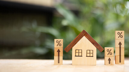 Wooden house with percentage blocks and upward arrows symbolizing rising mortgage rates and housing...