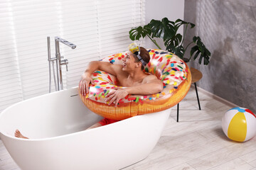 Happy man in with inflatable ring and diving mask chilling in bathtub at home. Dreaming about...