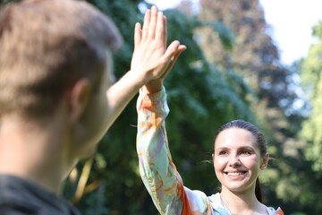 Obraz premium Young man with professional personal trainer giving high five outdoors