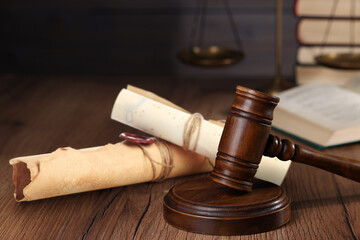 Fototapeta premium Judge's gavel and old rolled paper scrolls on wooden table