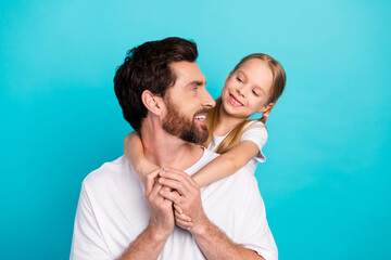 Father and daughter smiling together in a happy bonding moment on a teal background showcasing joyful family connections
