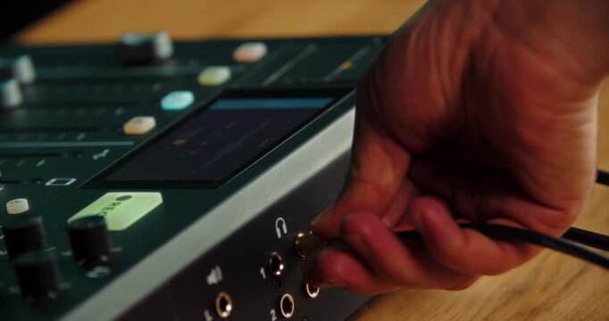 Hand plugging jack audio cable into professional sound mixer