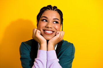 Cheerful young woman in casual outfit smiling brightly against vibrant yellow background with her...