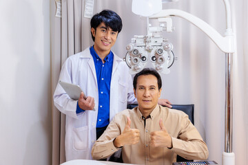 Young Asian Male Optician Assisting Mature Asian Male Patient During Eye Examination