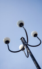 A low-angle shot of a street light with three globe-shaped lamps on curved black arms, set against...