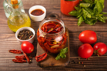 Dried organic tomatoes preservation with herbs and olive oil in jar.