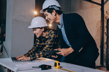 Construction manager and engineer dressed in orange work vests and hard helmets explore...