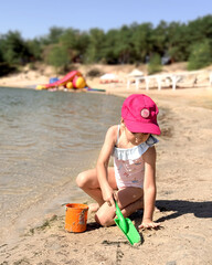 A girl plays in the sand with toys.