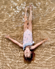 The girl swims in the water, lying on her back.
