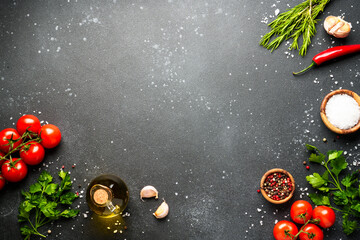 Food background with fresh vegetables, herbs and spices on black.