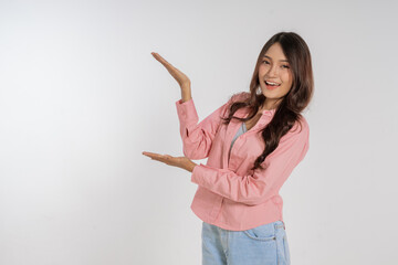 A cheerful woman joyfully showcasing something while smiling brightly on a plain backdrop