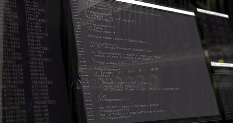Displaying computer monitor presenting JavaScript code in dimly lit office, with secondary monitor