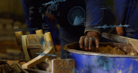 Mixing craftsman's hands plunging into clay mixture at blue tub in workshop, with mallet and trowel