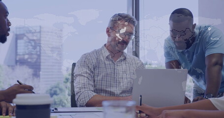 Collaborating colleagues analyzing documents around office desk, with laptop and world map overlay