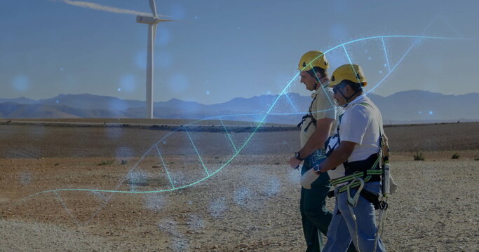 Walking two technicians in yellow safety gear crossing wind farm, DNA helix overlay, copy space