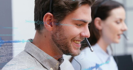 Smiling male call center agent speaking into headset at office desk, with holographic code overlays