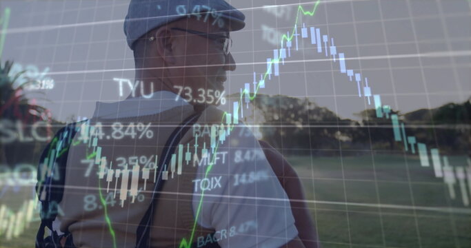 Standing Chinese man wearing flat cap and backpack in grassy field, with clear stock chart overlays - Powered by Adobe