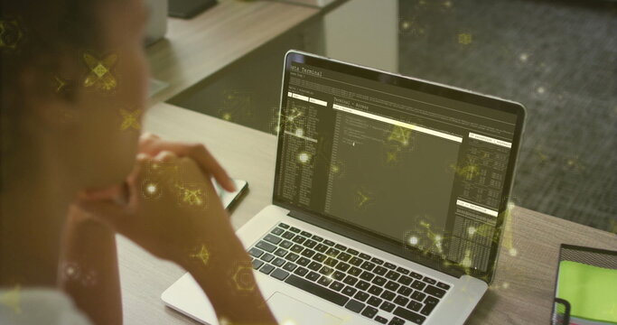 Woman wearing casual top reviewing laptop terminal at office desk, with phone notebook, copy space - Powered by Adobe