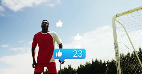 Standing man in jersey checking smartphone near goalpost, thumbs-up bubble showing 23, copy space