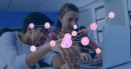 Collaborating teenage students typing on laptop in classroom, with digital network overlay