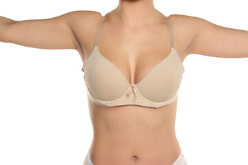 Studio shot of torso of young woman in beige bra raising arms posing on white background.