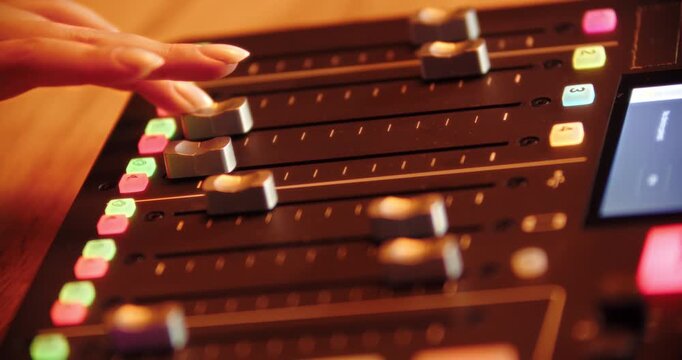 Close up of hand moving faders on professional audio mixer
