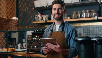 Glad Caucasian barista waiter male man guy bartender worker typing tablet order online app device...