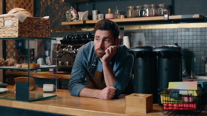 Disappointed Caucasian waiter man barista boredom in cafeteria exhausted employer problem bartender male entrepreneur leaning counter waitstaff overworking cafe guy contemplate small business stress