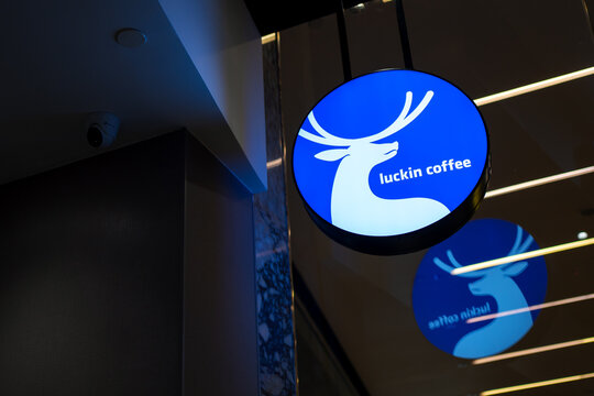 KUALA LUMPUR, MALAYSIA - AUG 16, 2025: Illuminated Luckin Coffee logo sign mounted indoors with a reflection on the ceiling panel.