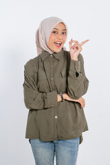 A joyful young woman wearing a casual outfit is excitedly pointing while displaying a bright smile