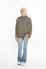 Obraz premium A stylish woman is dressed in an olive green shirt paired with jeans, complemented by a hijab