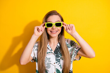 Cheerful young woman wearing stylish tropical shirt and bright sunglass posing against vibrant...