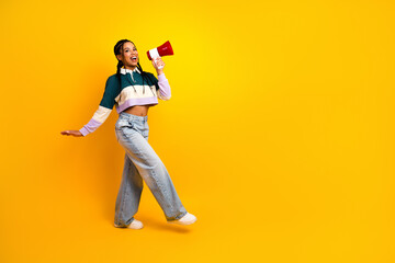 Energetic young woman in colorful casual attire holding a megaphone on a vibrant yellow background...