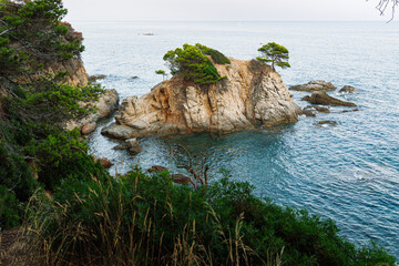 Beautiful rocky coast of Fenals in Lloret de Mar, featuring turquoise waters, rugged cliffs, and...