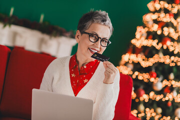 Elderly Woman Shopping Online with Credit Card Near Festive Christmas Tree in Cozy Home