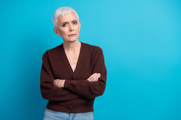 Portrait of a senior woman with crossed arms and a thoughtful expression in stylish casual attire...