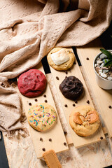 Flat lay of six gourmet cookies—red velvet, chocolate, sprinkle, speculoos and marshmallow—on wooden boards with chips; modern studio background for menus, social posts, and ads.