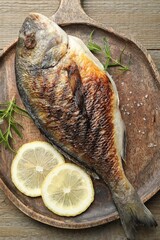 Tasty roasted dorado fish and spices on wooden table, top view. Homemade seafood dish