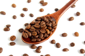 On a white background lies a wooden spoon with coffee beans.	