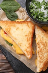 Delicious sandwiches with melted cheese and spinach on wooden table, flat lay