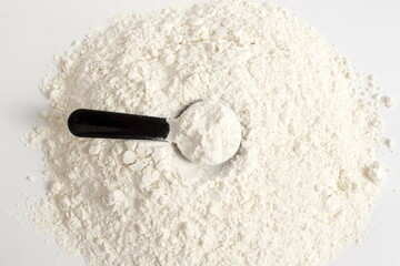 On a white background, a pile of wheat flour with a spoon is healing.