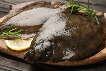 Fresh flounder fish, lemon and rosemary on wooden table, closeup. Raw seafood