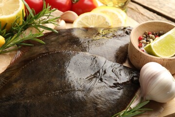 Fresh flounder fish, spices and products on wooden table, closeup. Raw seafood
