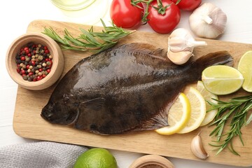 Fresh raw flounder fish and ingredients on white wooden table, flat lay. Seafood