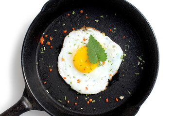 On a white background there is a cast iron frying pan with a fried egg.	