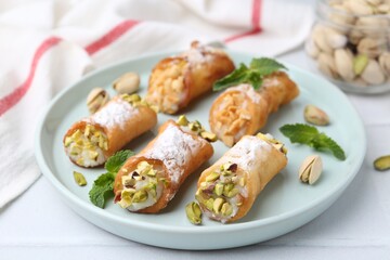 Delicious cannoli with cheese, nuts and mint on white table, closeup